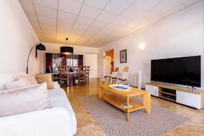 Ein modernes Wohnzimmer mit Sofa, Couchtisch, Fernseher und Essbereich.