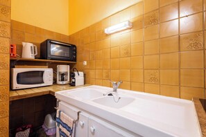 Eine Küche mit einer weißen Spüle, einer Mikrowelle, einem Toaster und einer Kaffeemaschine auf der Arbeitsplatte.