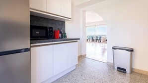 Una cucina moderna con mobili bianchi, un forno a microonde e un cestino.