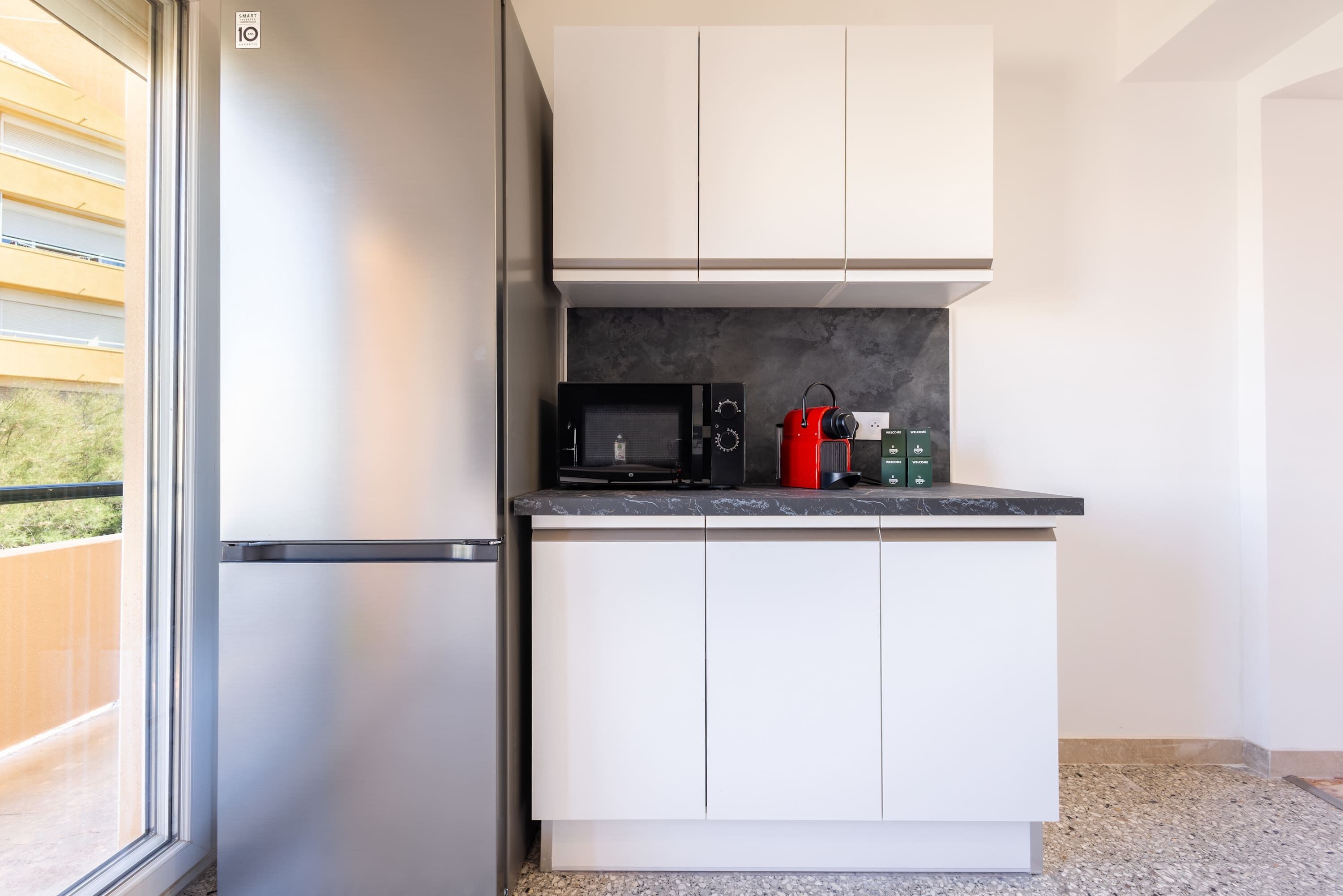 A compact kitchen with a refrigerator, microwave, and cabinets.