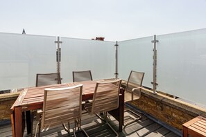 Et træbord og stole på en balkon med udsigt.