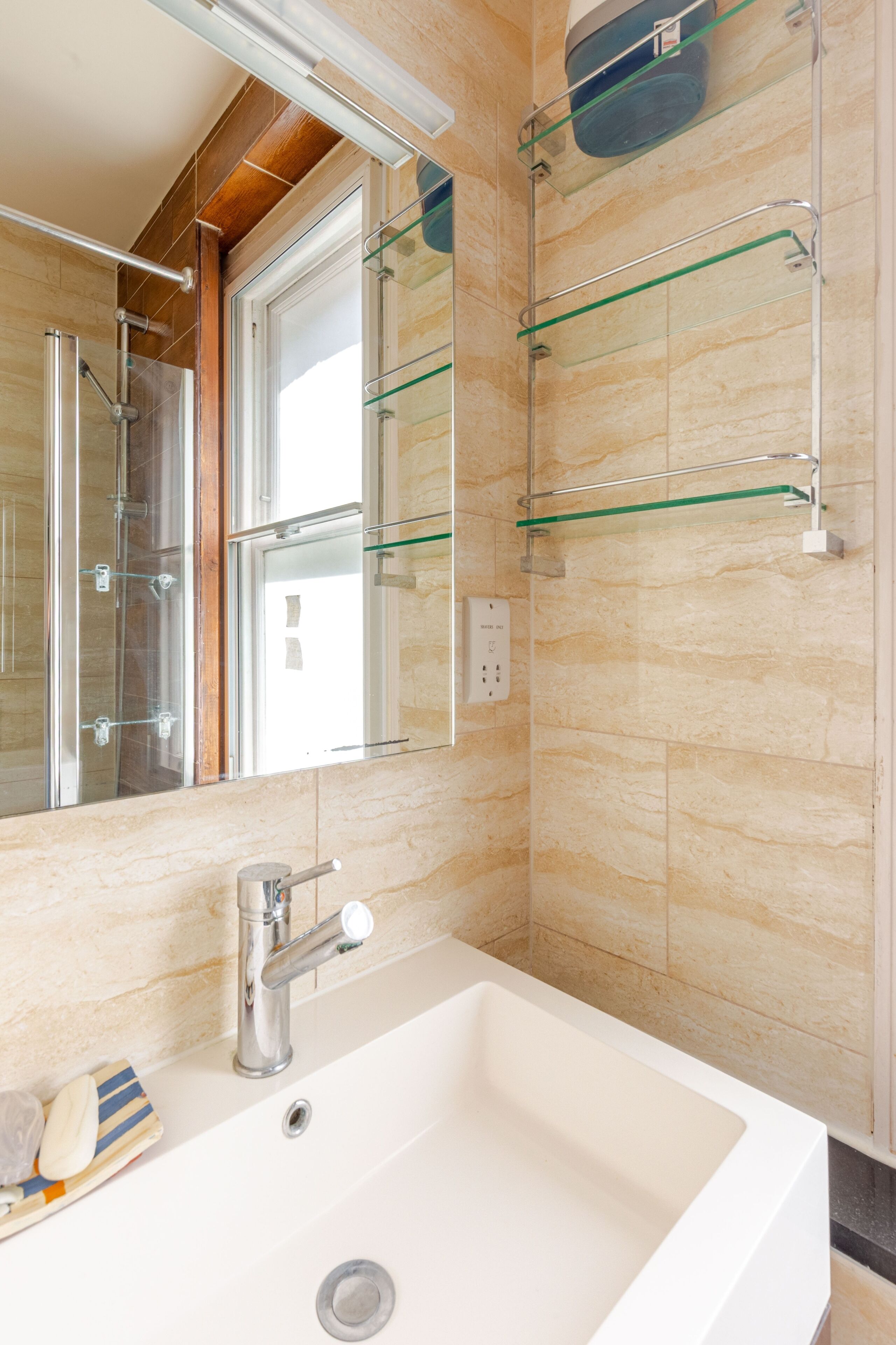 A bathroom with a white sink, a glass shower enclosure, and a mirror.