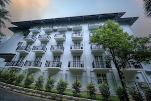 A multi-story building with balconies, a flat roof, and a fence with greenery. - BPR Asgiriya - Kandy (Kandy)