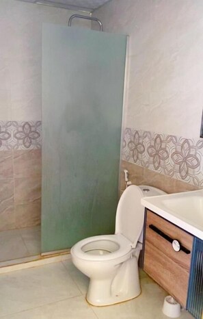 Un baño con inodoro, cabina de ducha y lavamanos.