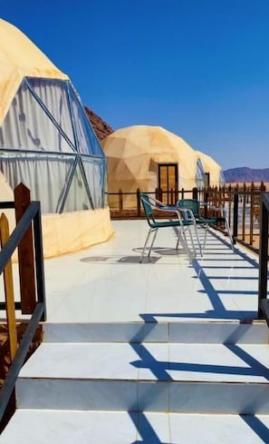 A series of yurts with a paved pathway leading to them, a wooden fence, and a clear blue sky. - LAVRA lUXURY CAMP (Aqaba)