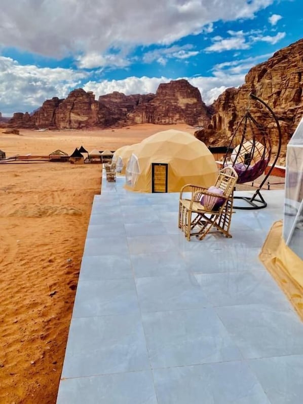 A desert landscape with tents and a swing chair.