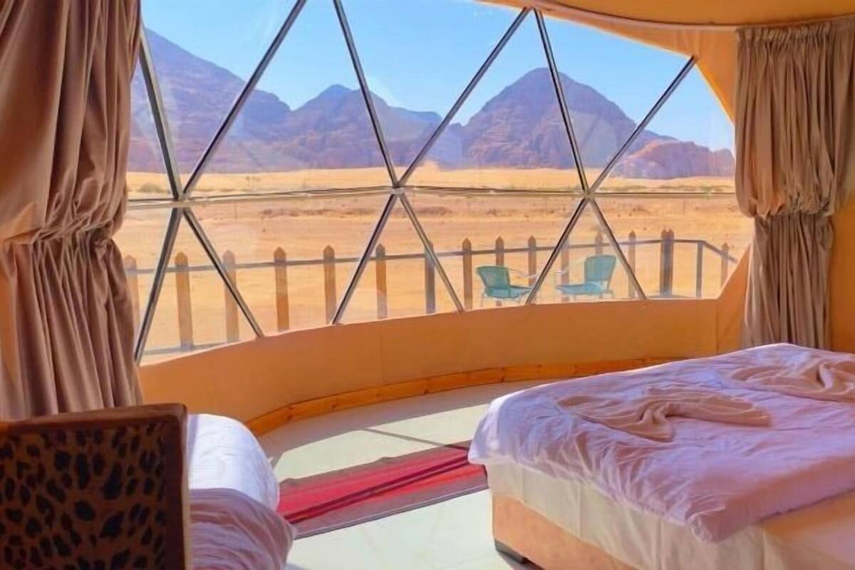 A tent with a bed, a chair, and a view of mountains.