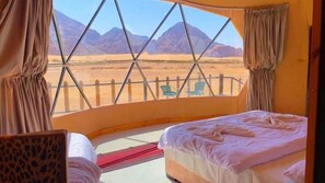 Een tent met een bed, een stoel en uitzicht op bergen.