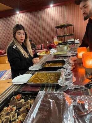Ein reichhaltiges Buffet mit verschiedenen Speisen, einer Kerze und einer gestreiften Wand im Hintergrund.