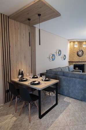 Ein moderner Essbereich mit Holzboden, einem gedeckten Esstisch und einem grauen Sofa im Hintergrund.