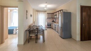 Eine kompakte Küche mit Esstisch und Stühlen, inklusive Kühlschrank und Herd.