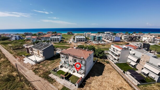 Ein Küstenwohngebiet mit modernen Gebäuden, blauem Himmel und Blick auf das Meer.