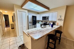 A kitchen with white cabinets, a black refrigerator, a microwave, and a marble countertop. - VLP 57 - easy access to heated pool and amenities! (Saint Augustine)