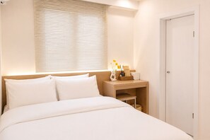 A neatly made bed with white linens, a bedside table with a lamp, a small basket, and a card. - Yoonstay Haenggung (Suwon-si)