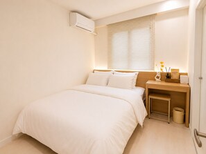 A bedroom with a bed, bedside table, lamp, and an air conditioning unit. - Yoonstay Haenggung (Suwon-si)