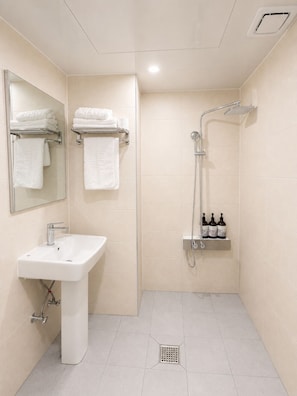 A modern bathroom with a sink, mirror, towel racks, shower, and toiletries. - Yoonstay Haenggung (Suwon)