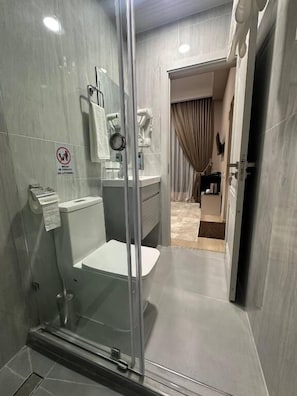 Un baño moderno con cabina de ducha de vidrio, inodoro y lavabo.