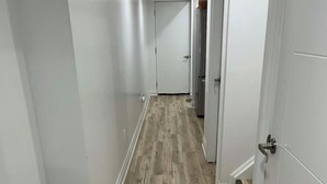 Un corridoio con pavimento in legno e pareti bianche.