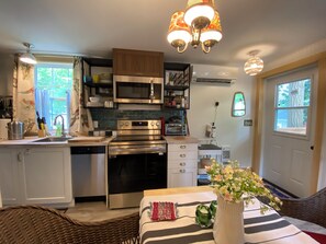 Una cocina moderna con electrodomésticos de acero inoxidable, un comedor con mantel a rayas y un jarrón decorativo con flores.