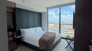 Ein modernes Schlafzimmer mit einem großen Bett, Blick auf die Stadt und einem eingebauten Kleiderschrank.