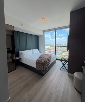 Ein modernes Schlafzimmer mit einem großen Bett, Blick auf die Stadt und einem eingebauten Kleiderschrank.