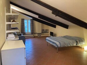 Ein Zimmer mit einem Bett, einem Schreibtisch, einem Stuhl, einem Fernseher und einem Fenster mit Vorhängen.