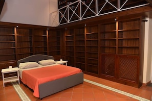 Ein Schlafzimmer mit einem Bett, Nachttischen, einem Bücherregal und einem Holzschrank.