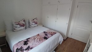 Un dormitorio con cama, armario blanco y una puerta.