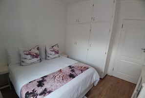 Un dormitorio con cama, armario blanco y una puerta.