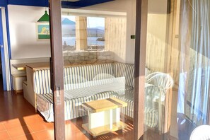 Ein Zimmer mit einem gestreiften Sofa, einem kleinen Holztisch, einer Steinwand und Blick aufs Meer.