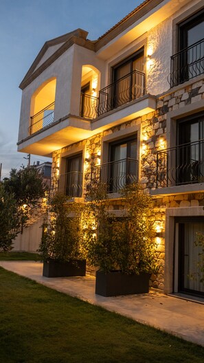 A multi-story building with balconies, stone facade, and outdoor lighting. - Canata Hotel Çeşme (Cesme)