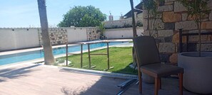 A poolside area with a stone wall, a chair, and a large planter. - Canata Çeşme (İzmir)