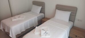 Two single beds with white linens and pillows, each with a name tag. - Canata Çeşme (İzmir)