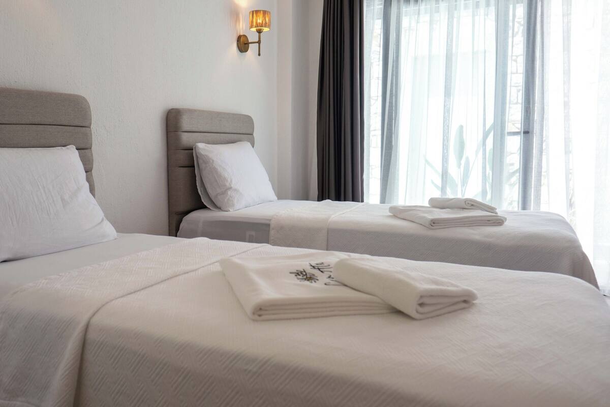 A hotel room with two beds, each with a pillow and a folded towel.