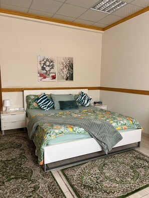 Ein Schlafzimmer mit einem Bett, Nachttischen, einem Teppich und zwei an der Wand hängenden Bildern.