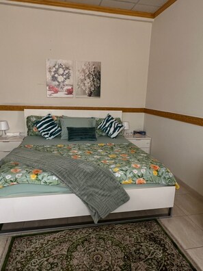 Ein Schlafzimmer mit einem Bett, zwei Nachttischen, einem Teppich und floralen Wandbildern.