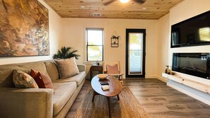 A living room with a sofa, a coffee table, a chair, a television, and a fireplace. - The perfect APT near everything! (Rio grande)
