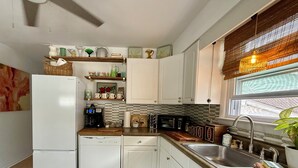 A compact kitchen with white cabinets, a coffee maker, a microwave, and a sink. - Botanical 2BR, steps to Hawk Haven, near Beaches (rio grande)
