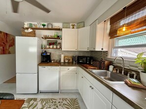 A compact kitchen with white cabinets, a coffee maker, a microwave, and a sink. - Charming 2BR, steps to Hawk Haven, near Beaches (rio grande)