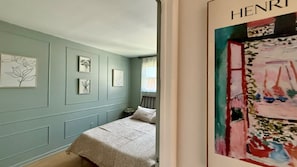 Une chambre à coucher avec un lit, une petite table de chevet et une fenêtre.