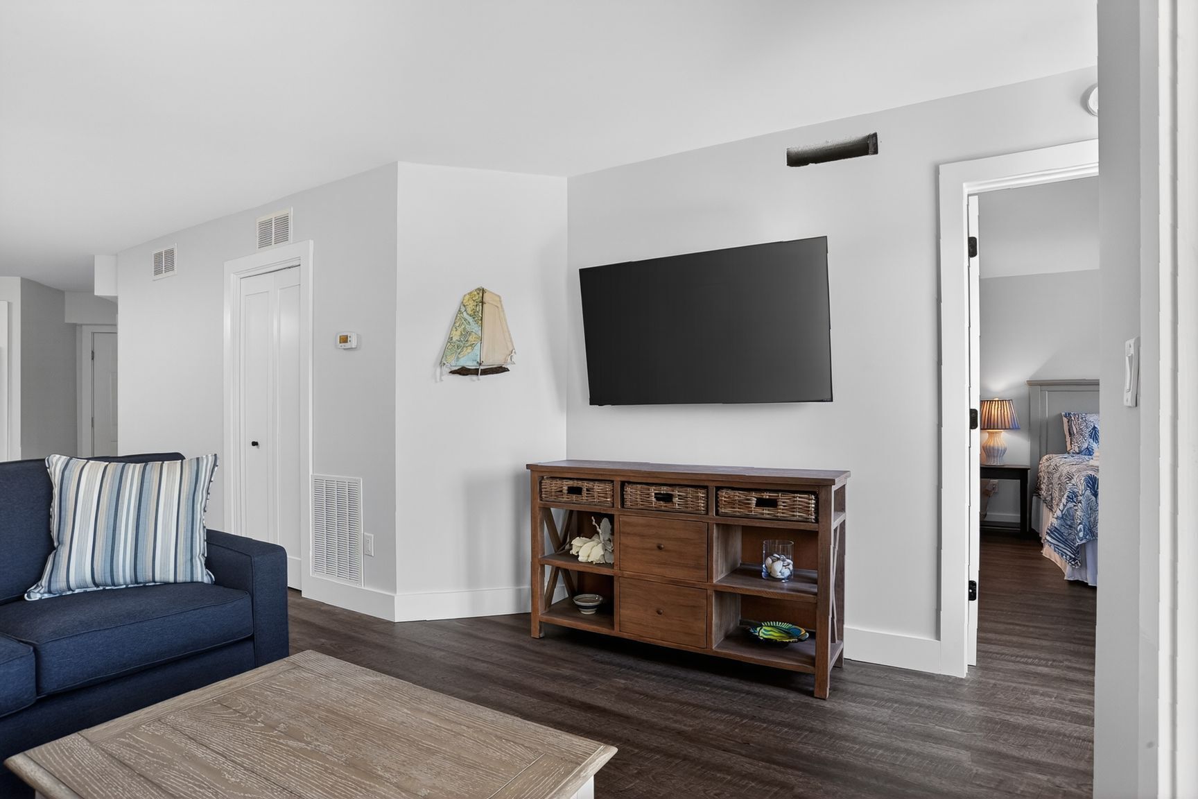 Una sala de estar con sofá, mesa de centro, televisor y un mueble de madera con cestas.