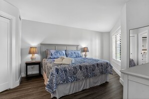 Een slaapkamer met een bed, twee nachtkastjes met lampen, een dressoir en een raam met zonwering.