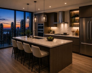 A modern kitchen with a large island, bar stools, stainless steel appliances, and a city view. - Greenhill Resort Cameron Highland (Tanah Rata)