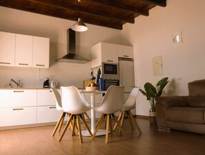 A modern kitchen with white cabinets, a central island with chairs, a microwave, oven, and a large plant. - Cozy and bright house in a central area of the island. (Tías)