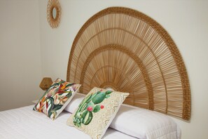 A bed with a woven headboard, two decorative pillows, and a wall-mounted mirror. - Cozy and bright house in a central area of the island. (Tías)
