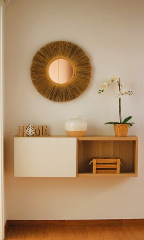 A wall-mounted mirror, a white vase, wooden letters spelling 'HOME,' a small wooden shelf, and a potted orchid. - Cozy and bright house in a central area of the island. (Tías)
