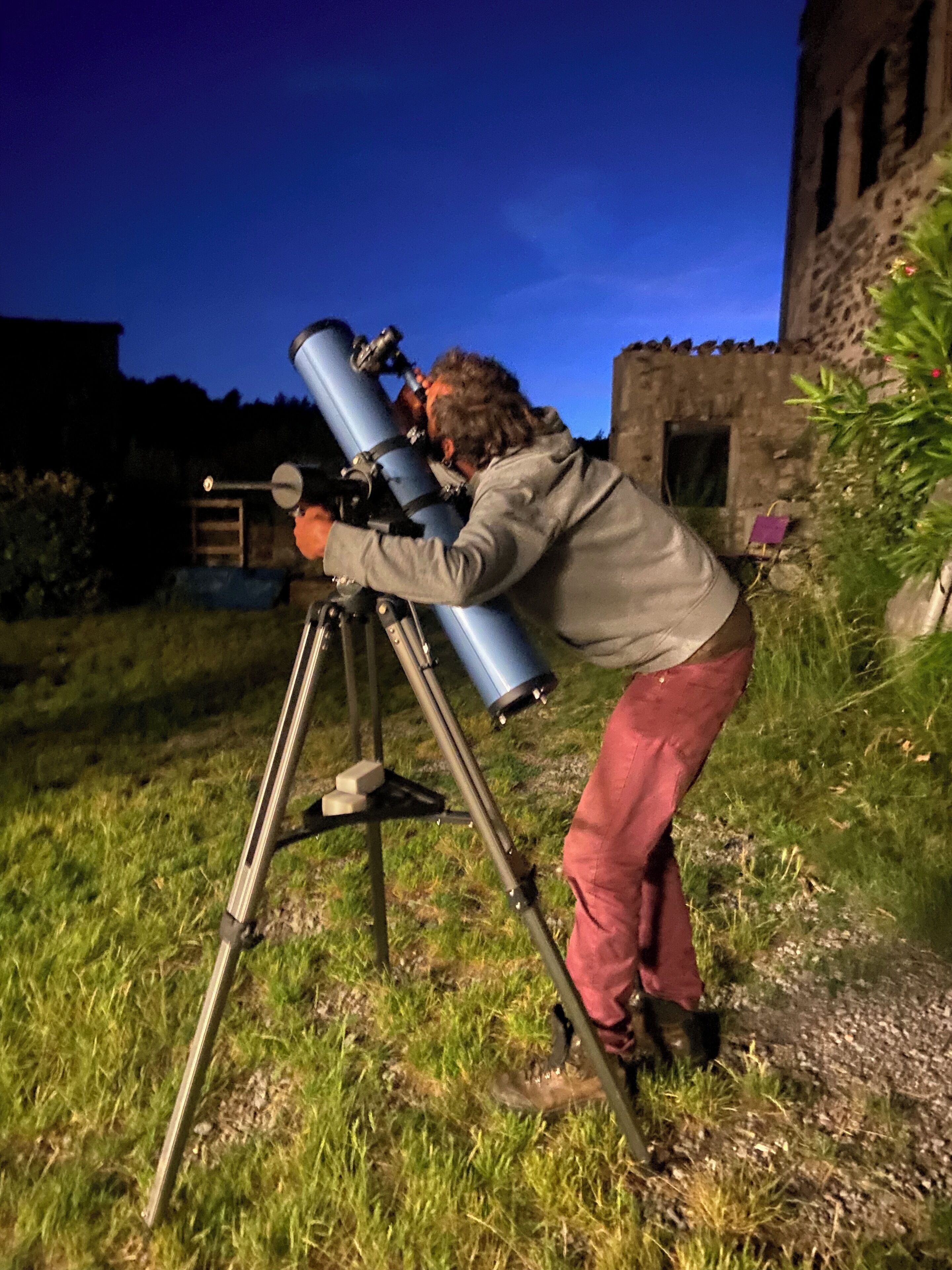 A person using a telescope on a tripod outdoors.