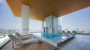 A rooftop pool with lounge chairs, a wooden ceiling, and a city view. - Cozy Stay at Casa Mira Towers Guadalupe (Cebu City)