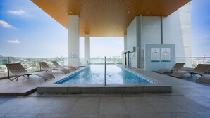 A rooftop pool with lounge chairs, a wooden ceiling, and a city view. - Cozy Stay at Casa Mira Towers Guadalupe (Cebu City)