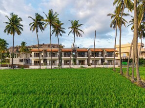 Un hotel con varios pisos, balcones y vistas a un campo verde.